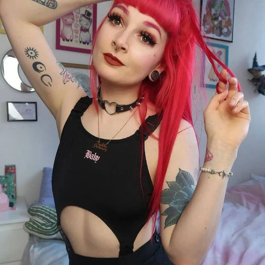 Bright pink-haired model wearing a black 'Baby' Cut Out Bodysuit with a choker and tattoos.
